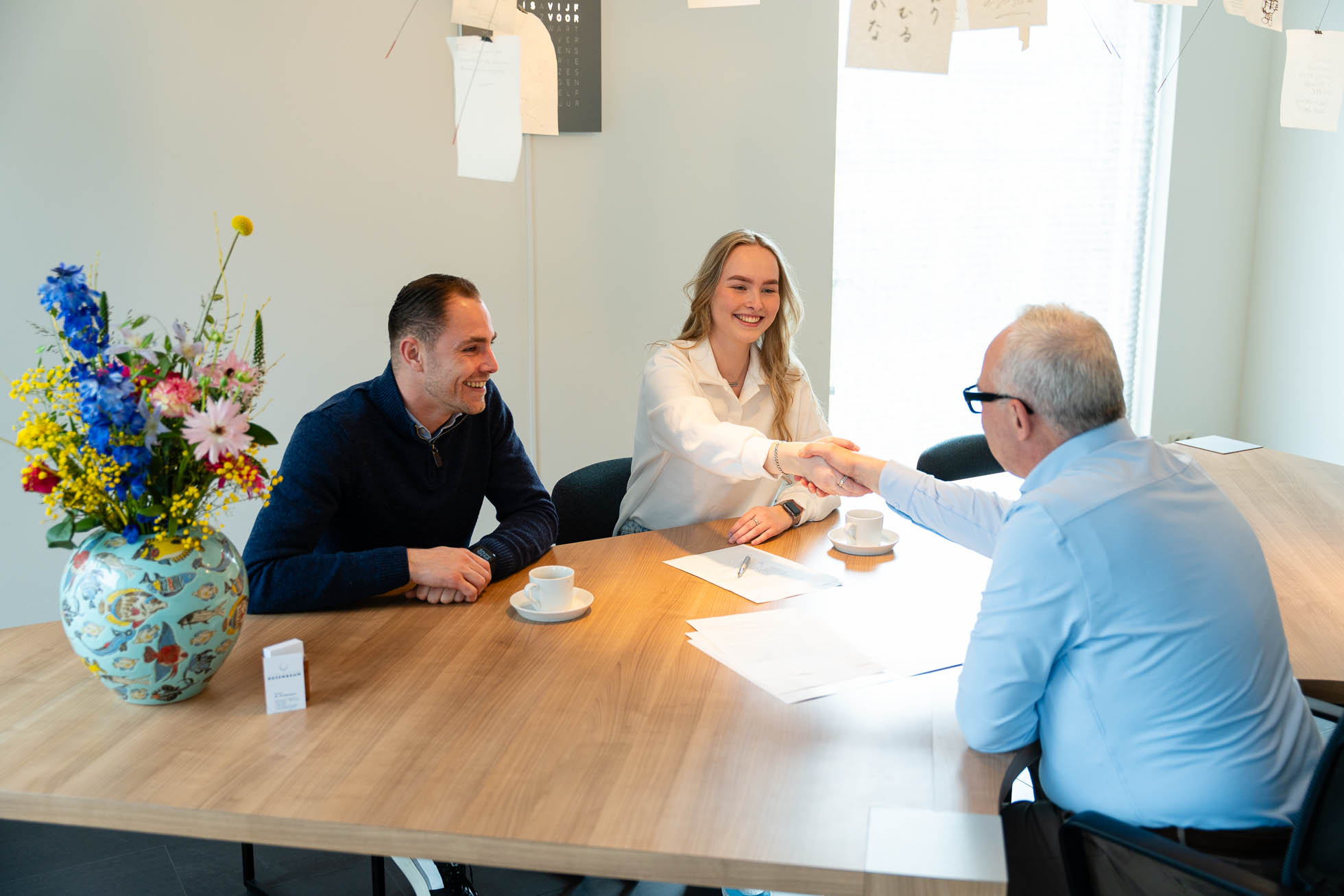 Mensen aan buro geven elkaar de hand
